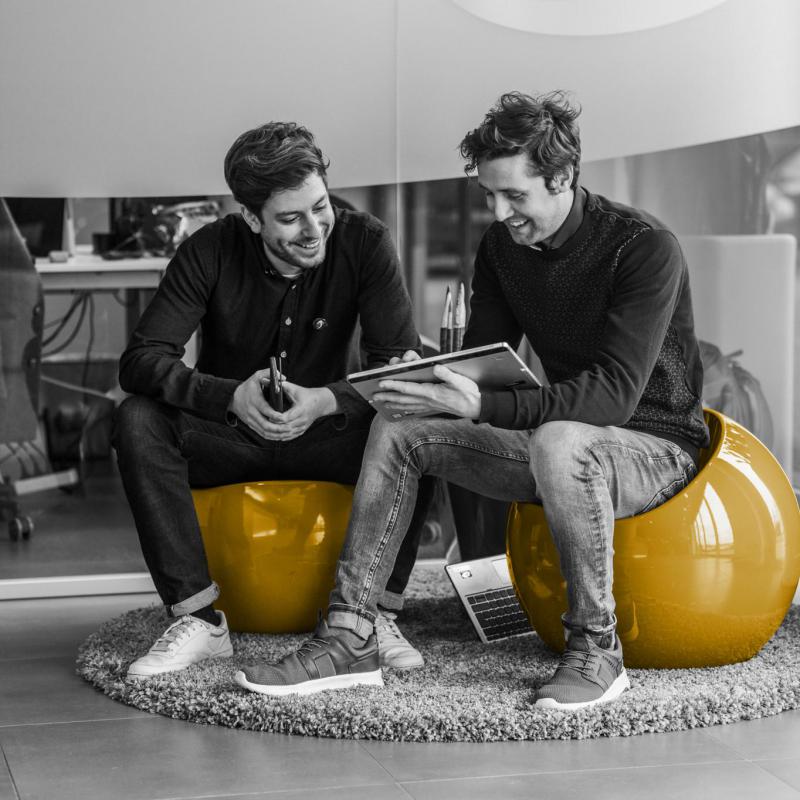 Twee lachende personen kijken samen op een surface tablet